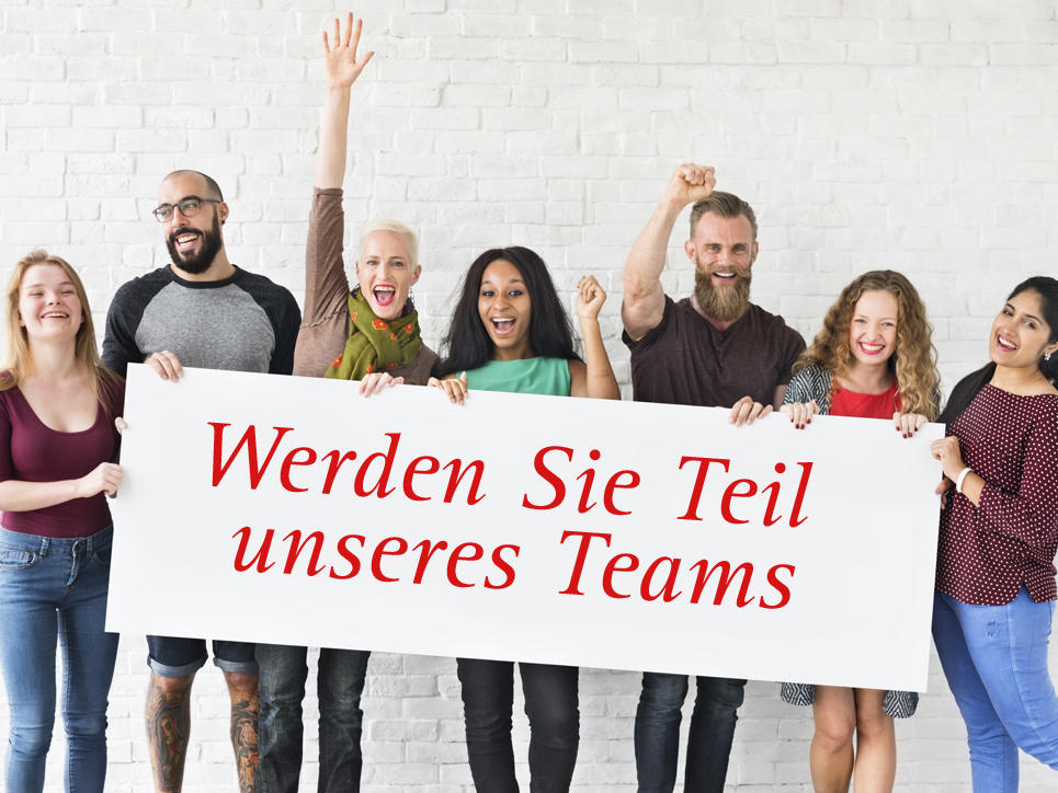 Mitarbeiter halten ein Plakat "Werden Sie Teil unseres Teams"